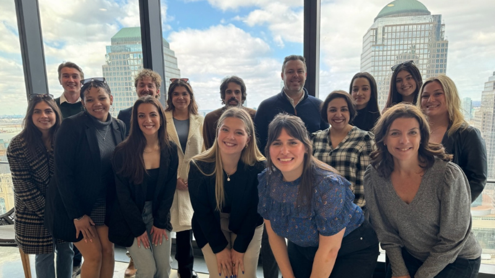 PRSSA students pose in front of a window overlooking New York City at AxiCom