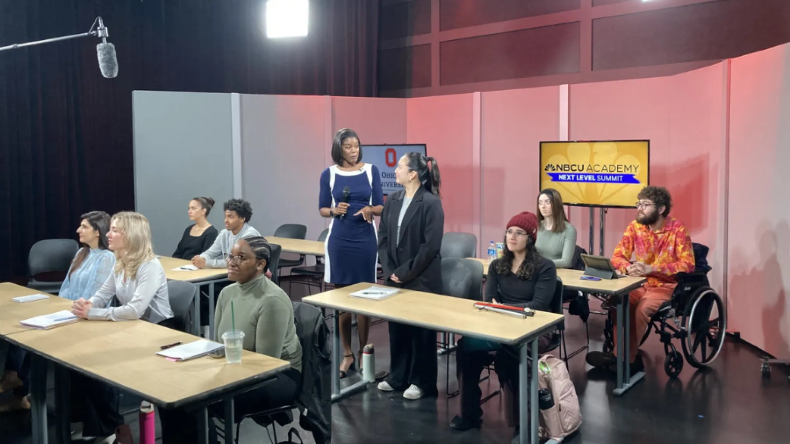 Students pictured participating in simulcast. A student is asking a question.