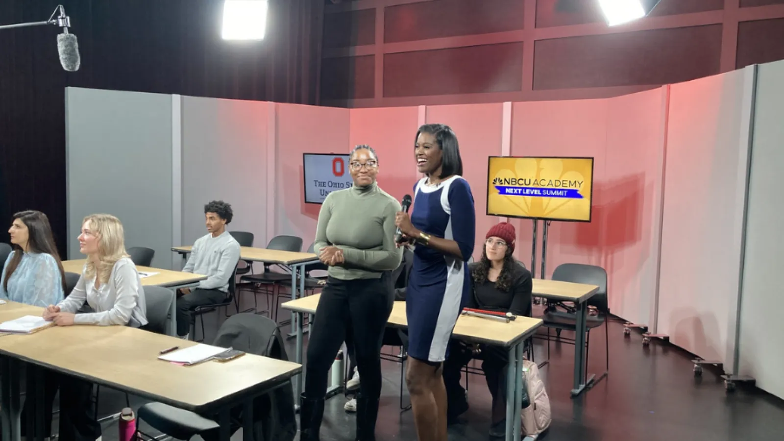 Students pictured participating in simulcast. A student is asking a question.