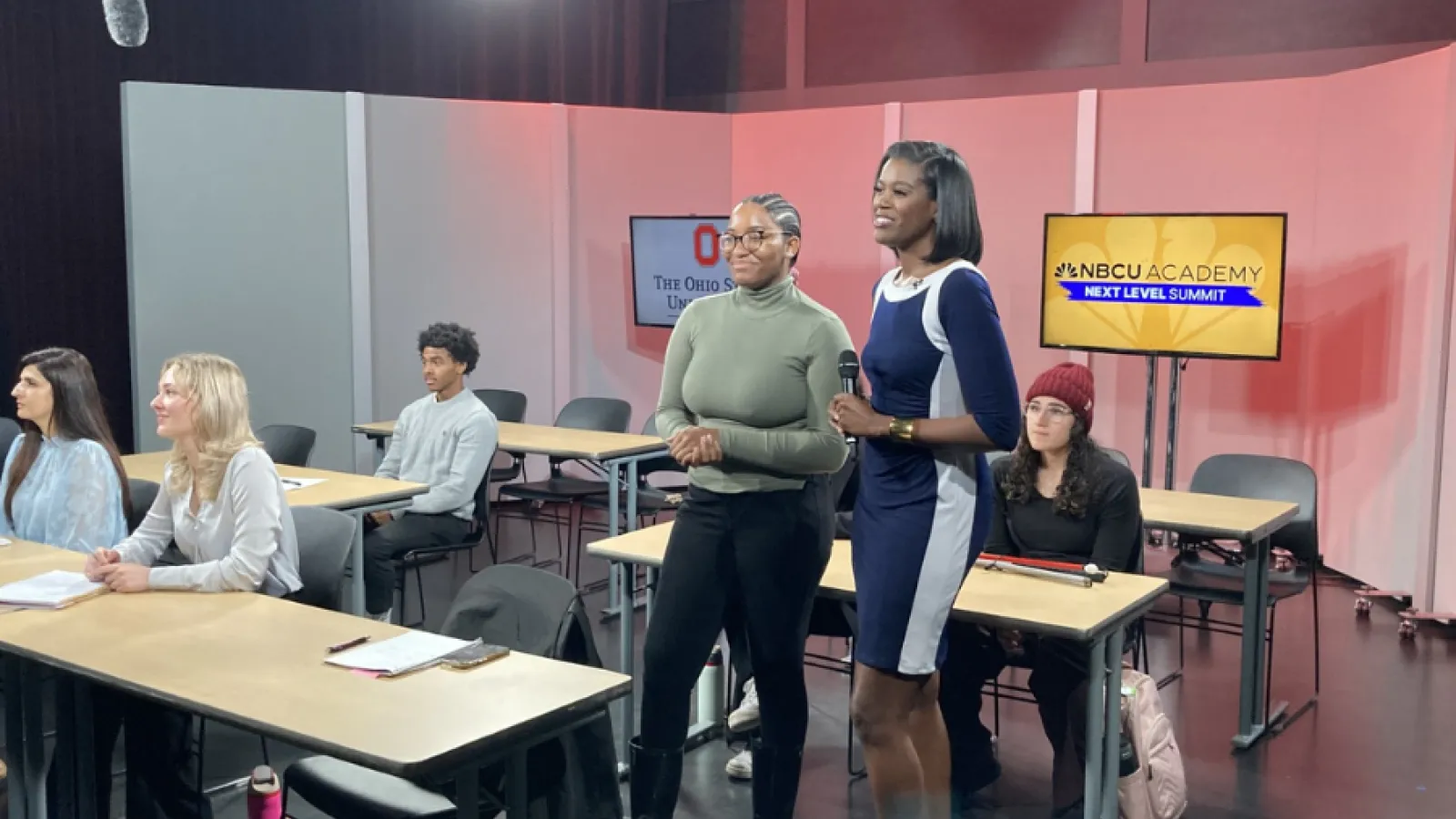 Students pictured participating in simulcast. A student is asking a question.