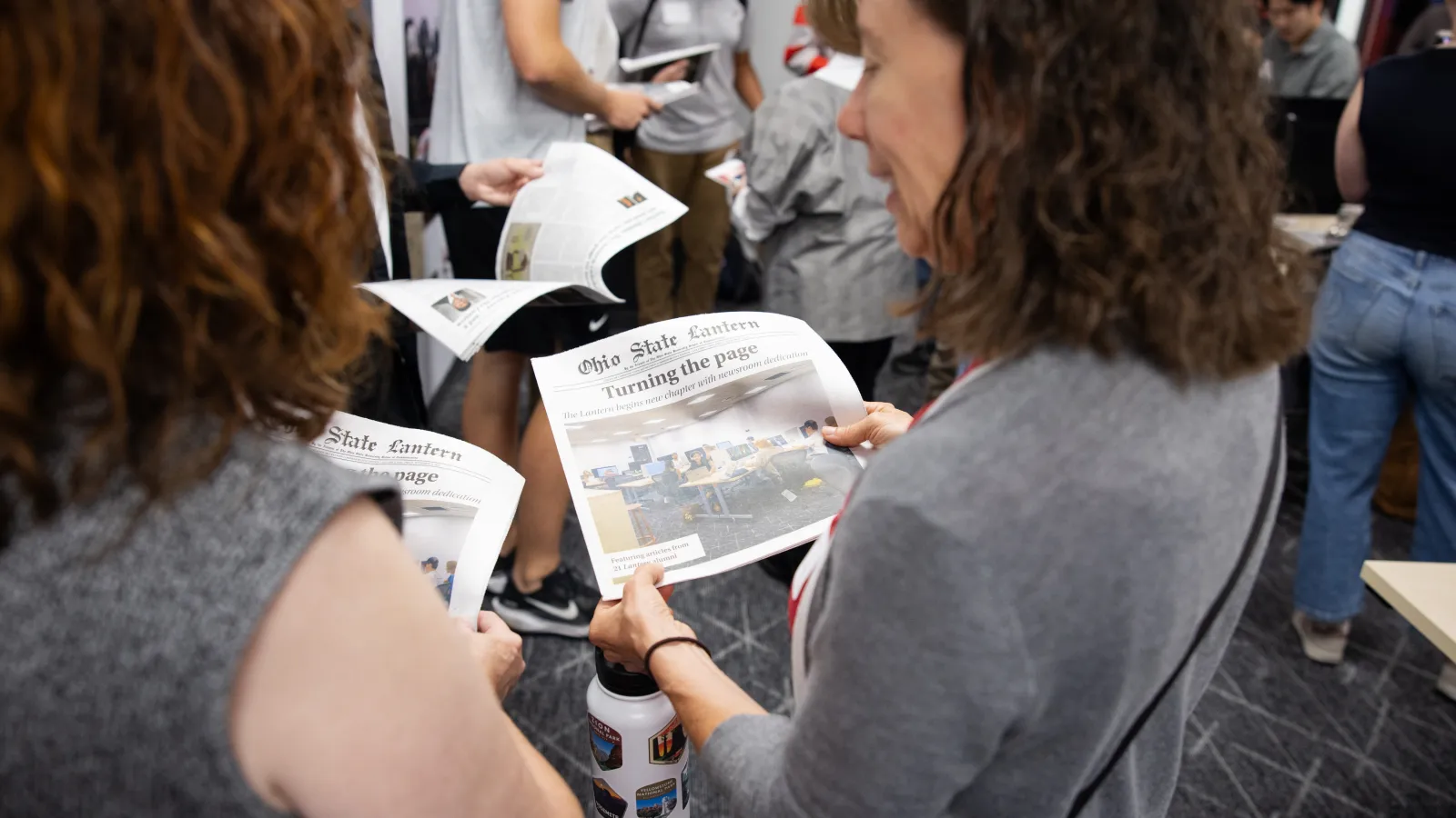 Alumni reading newspaper at Lantern Newsroom Dedication