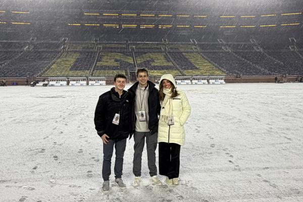 Undergraduate students pose on the field at Michigan Stadium 