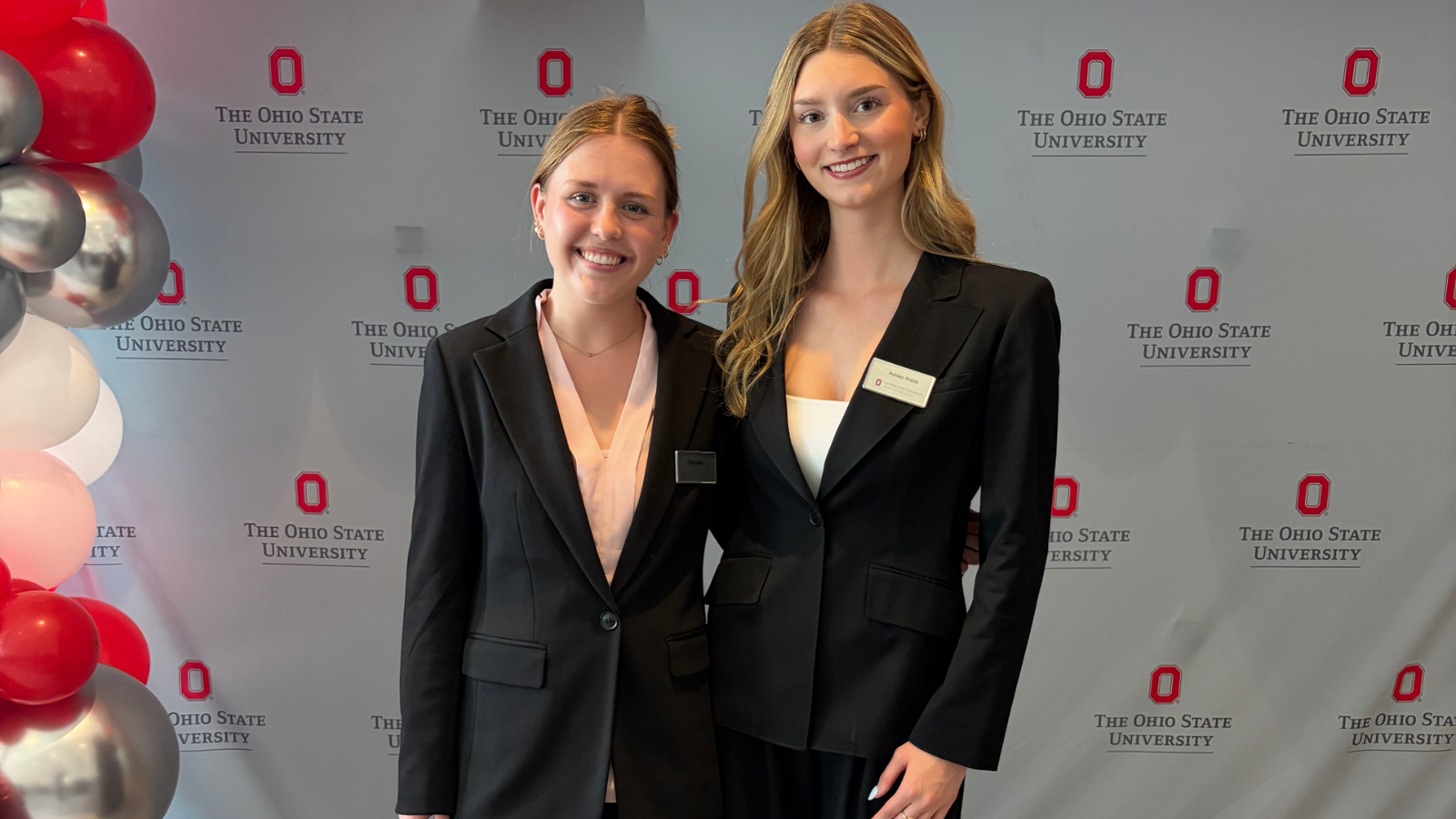 Two students standing in front of backdrop 
