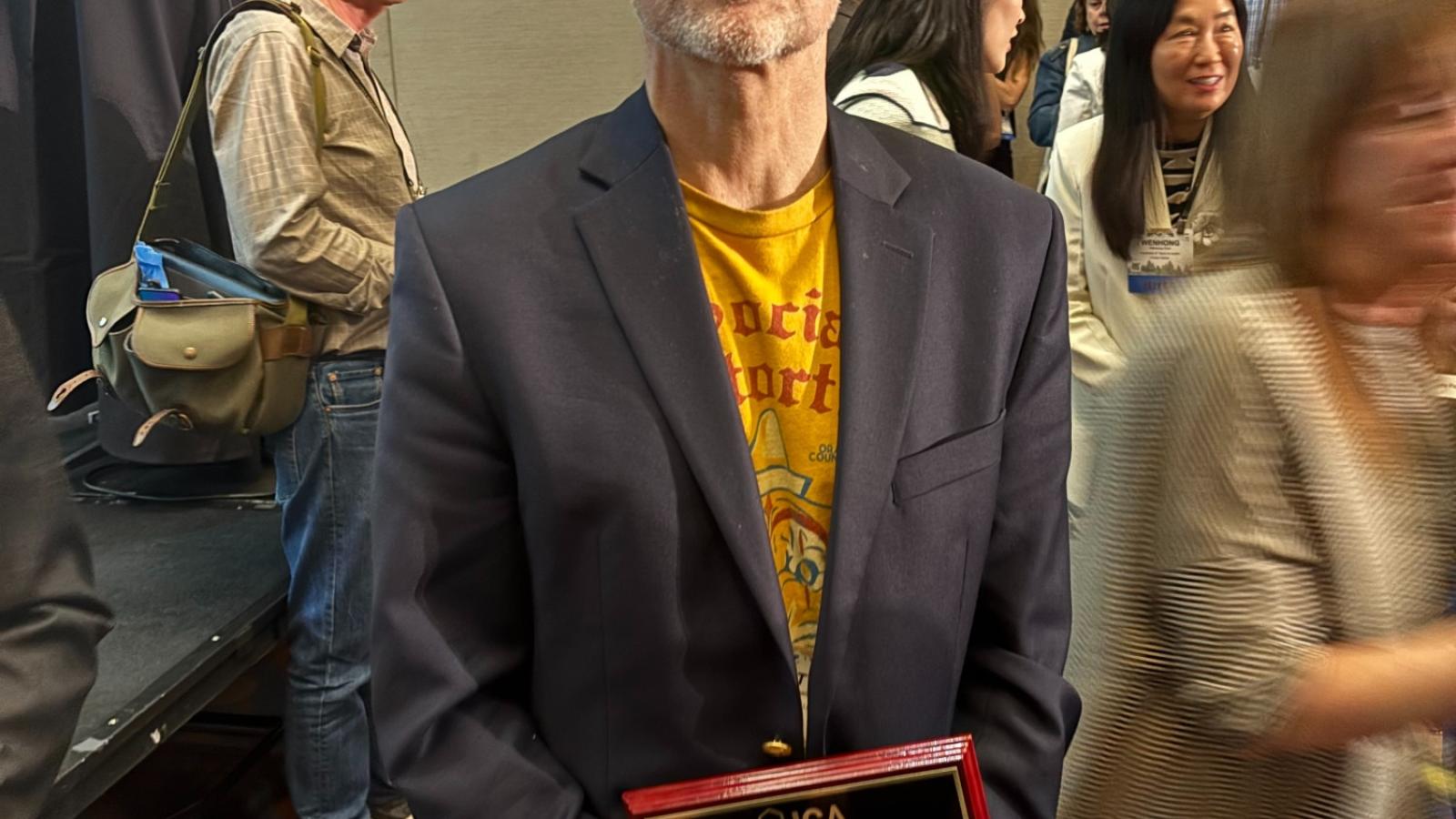 Scott Campbell holding his ICA Fellow award